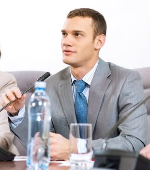 Portrait of a businessman, said into the microphone, the meeting