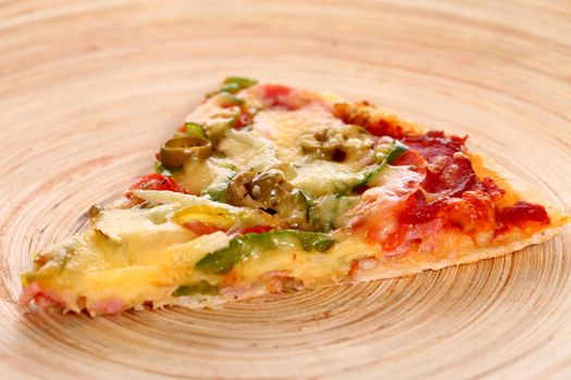 Slice of tasty italian pizza on a bamboo plate