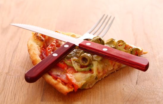 Slice of fesh italian pizza with fox and knife over wooden background