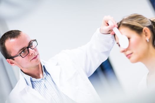 Optometry concept - pretty young woman having her eyes examined by an eye doctor