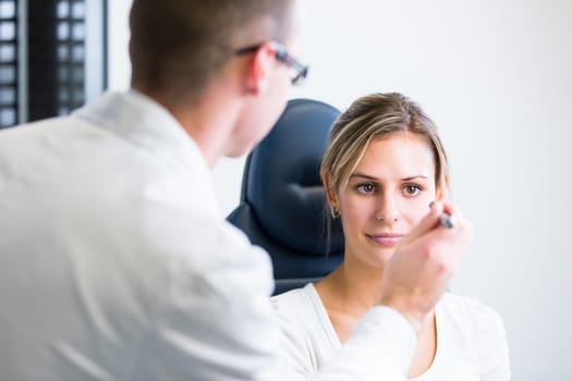 optometry concept - pretty young woman having her eyes examined by an eye doctor