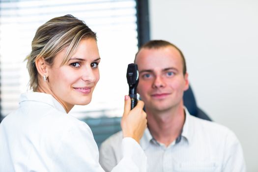 Optometry concept - handsome young man having her eyes examined by an eye doctor