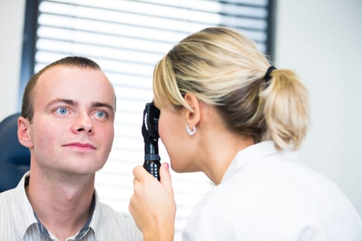 optometry concept - handsome young man having her eyes examined by an eye doctor