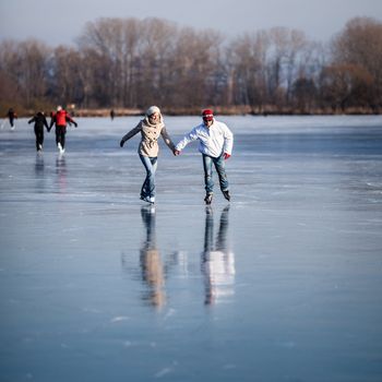 Couple ice skating outdoors on a pond on a lovely sunny winter day