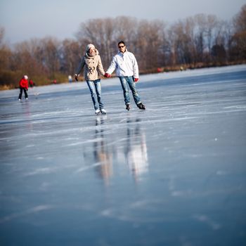 Couple ice skating outdoors on a pond on a lovely sunny winter day