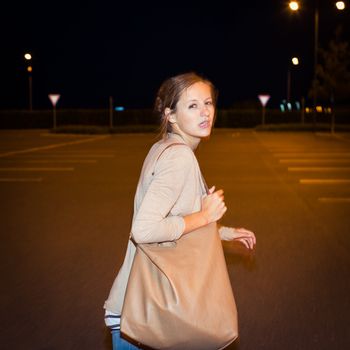 Scared young woman running from her pursuer in a deserted parking lot