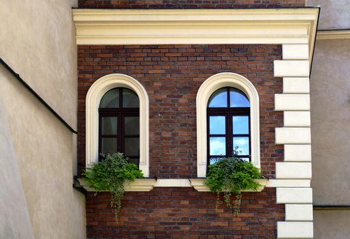 facade of an old house with arc windows and overgrown with flowers