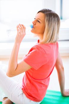 Pretty young woman refreshing during workout at home