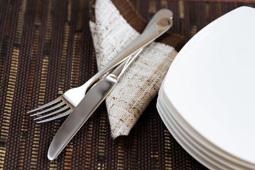 fork knife and empty plates on the background of brown material