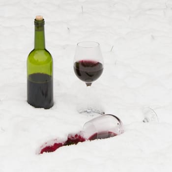 Bottle of red wine and wineglasses isolated in the cold snow