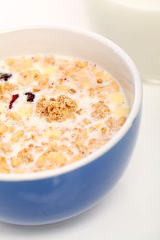 Image of blue bowl with healthy muesli and fresh milk isolated on white background