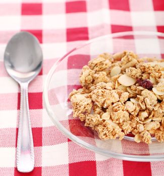 Healthy wholegrain muesli in a plate with silver spoon on a squared tablecloth