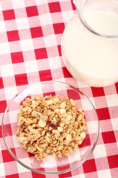 Healthy wholegrain muesli in a plate and a cup of milk on a squared tablecloth