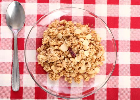 Healthy wholegrain muesli in a plate with silver spoon on a squared tablecloth