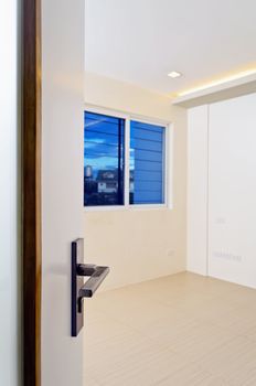 Newly built and painted room with wooden flooring. Focus on door knob.