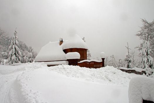 A lonely, snow-covered wooden house on the hillside