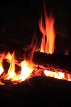 Burning logs of a sizzling campfire by night.