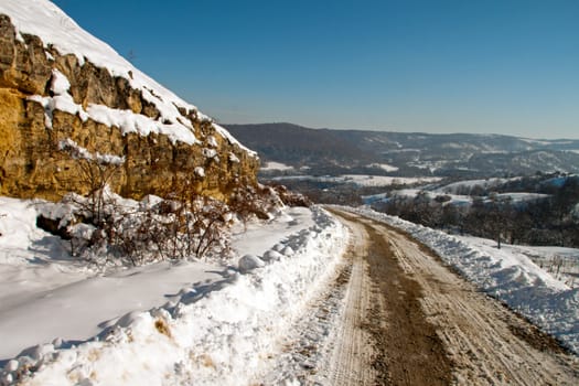 An empty, snowy serpentine with rocks and bushes