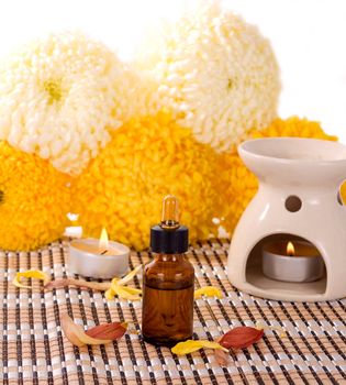 Aromatherapy oils and candles with small chrysanthemum flowers.
