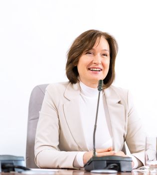 Portrait of a senior business woman at the meeting, sitting at a table on which are microphones