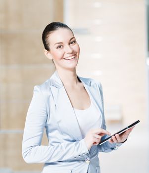 Portrait of a business woman in the tablet at the office, turned around and looking at the camera