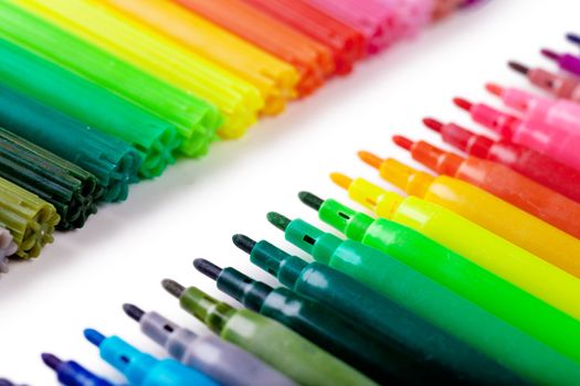 Closeup view of a row of colorful felt tip pens over white background