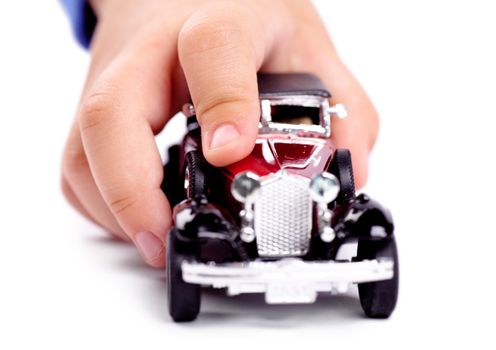 Macro view of child hand playing with toy car over white background