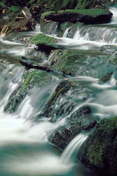 Mountain stream flowing over moss covered rocks, blurred water