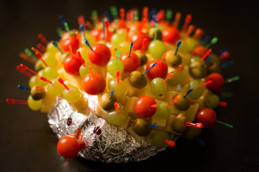 Cheese Hedgehog consisting of cheese sticks with tomatoes, olives and grapes into bread wrapped in silver foil