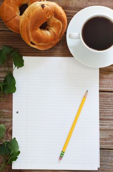 Paper and Pencil with Bagels and Coffee on wooden table