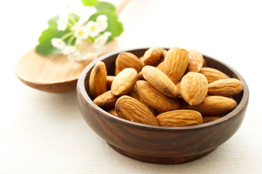 Almonds in wooden bowl with wooden spoon