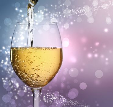 White wine being poured into a wine glass on abstract lights background
