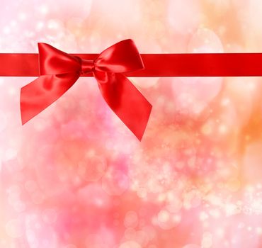Red bow and ribbon with red - orange bokeh lights background 
