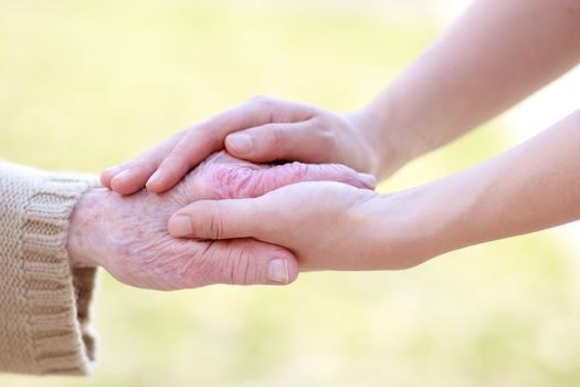 Senior lady and young women holding hands 