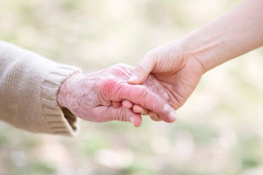 Senior lady and young women holding hands 