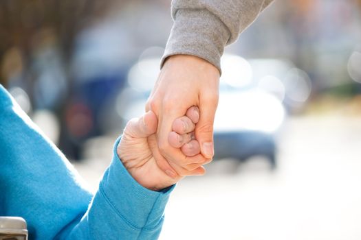 Young Caregiver Holding Senior's Hand Outside