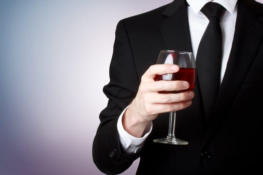 Elegant young man holding a glass of red wine 