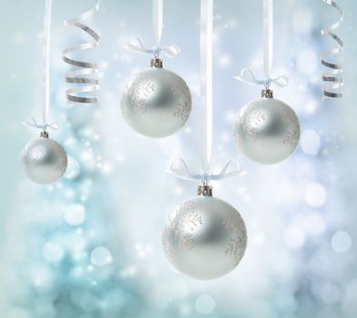 Silver Christmas Ornaments over glowing tree background