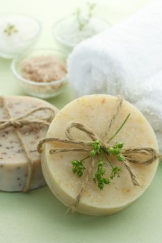 Bars of soap with bath salt and towels in light green background