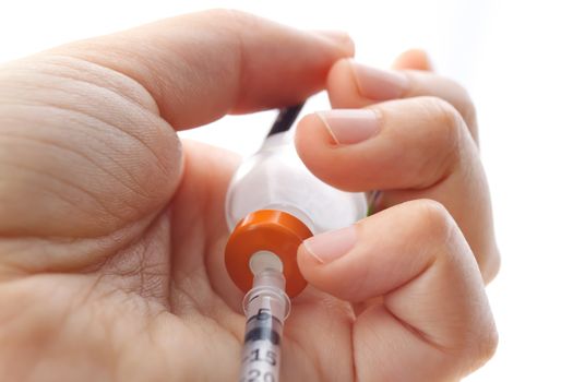 Hand holding syringe and vial on white background