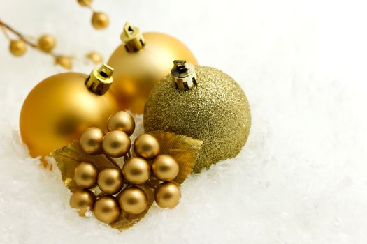 Gold christmas baubles and ornaments on white snow