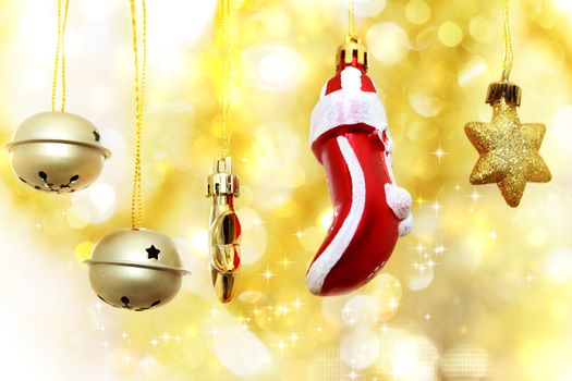 Christmas bells, glove and stars hanging over golden bokeh background