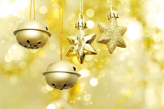 Christmas bells and stars hanging over golden bokeh background