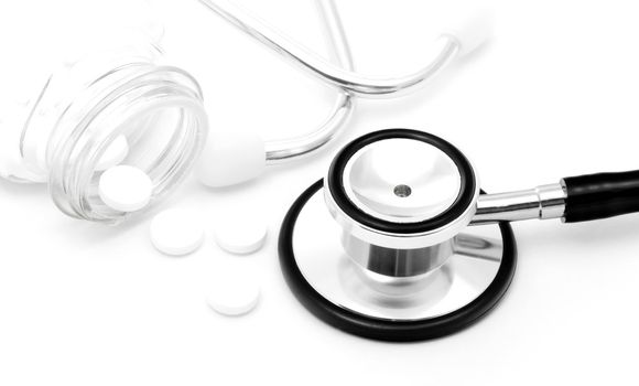 Stethoscope with pills on white background