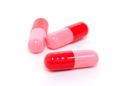 Red and pink colored capsules on white background