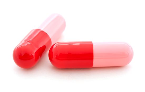 Red and pink colored capsules on white background