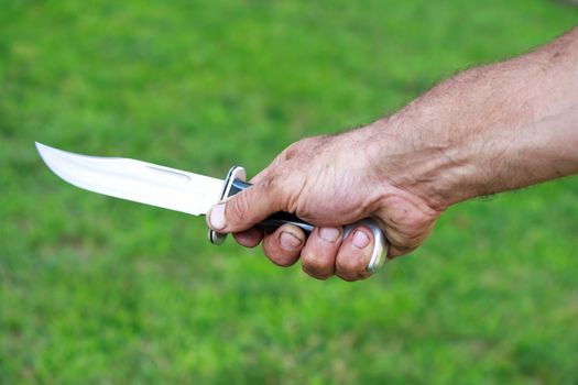 Man holding dagger over green lawn background