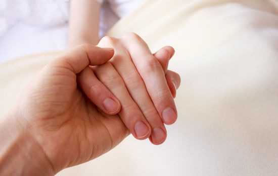 Holding the hand of a sick loved one in hospital bed