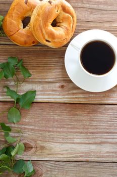 Cup of coffee with bagels on wooden table