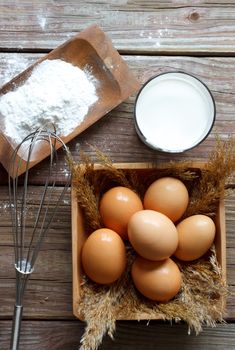 Eggs, flour and milk on wooden table